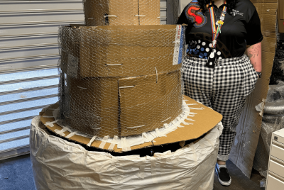 person standing next to large cardboard cake structure