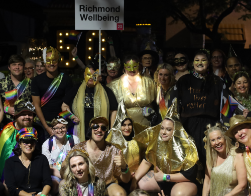 Large group of people in gold and rainbow outfits