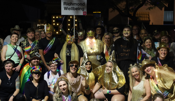 Large group of people in gold and rainbow outfits