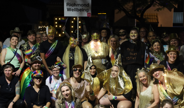 Large group of people in gold and rainbow outfits