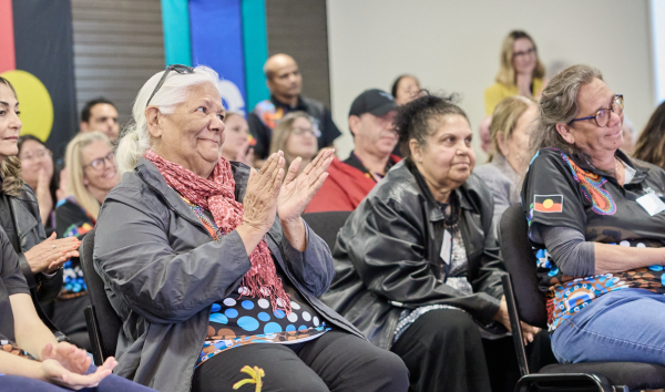 members of a crowd sitting and clapping