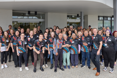 Large group of staff wearing staff t-shirts outside building entrance