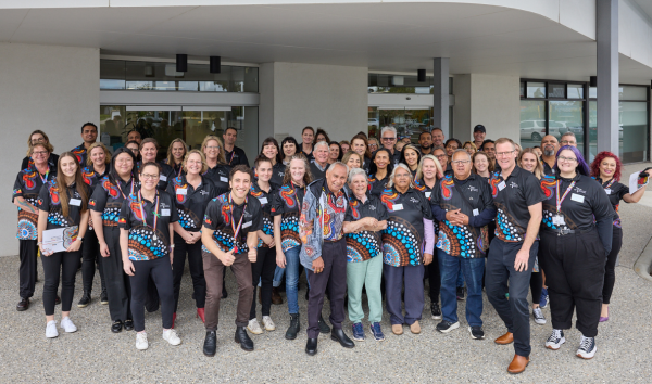 Large group of staff wearing staff t-shirts outside building entrance