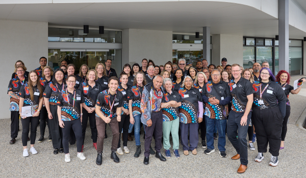 Large group of staff wearing staff t-shirts outside building entrance