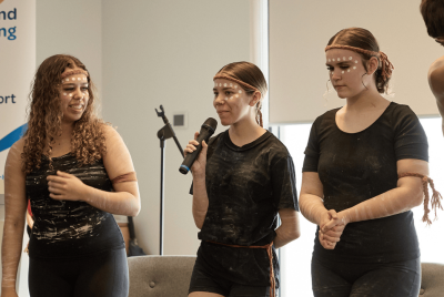 three girls speaking in traditional Aboriginal clothing