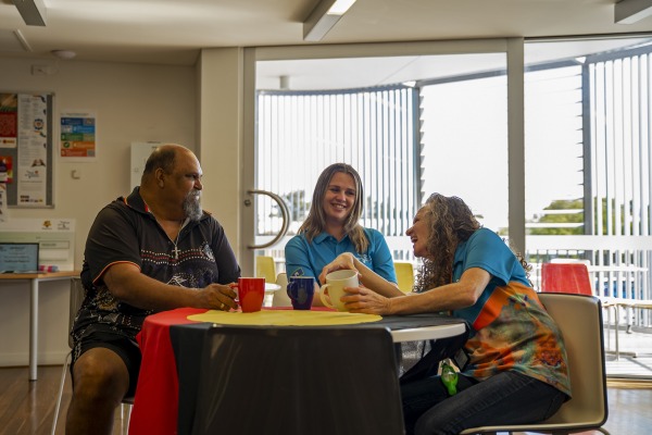 Three people sitting at a table laughing and smiling